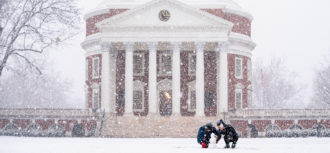 two people building a snowman in front of the rotunda